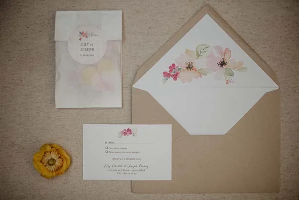 Magnifique invitation de mariage avec une étiquette fleurie et une illustration florale, accompagnée d'une fleur pliée