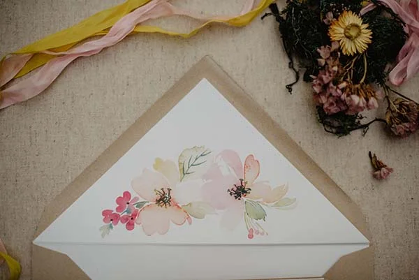 Magnifique invitation en papier avec des fleurs douces et des couleurs subtils, accompagnée de soigneusement pliées