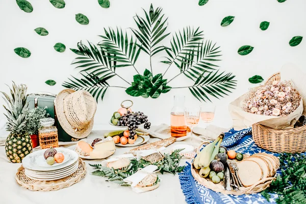 Table en plein air dégustante avec fruits frais et fromages, décoré de palmiers et de feuilles vertes, idéal pour un