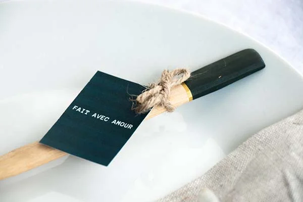 Un couteau de cuisine noir avec une manche en bois et une fourche en hache, accompagné d'un panneau vert avec