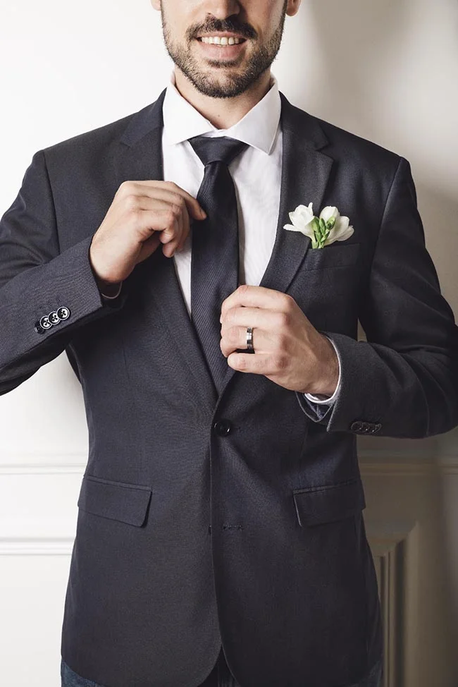 Élegance et sophistication incarnée dans un costume noir immaculé, accompagné d'une fleur blanche discrète au