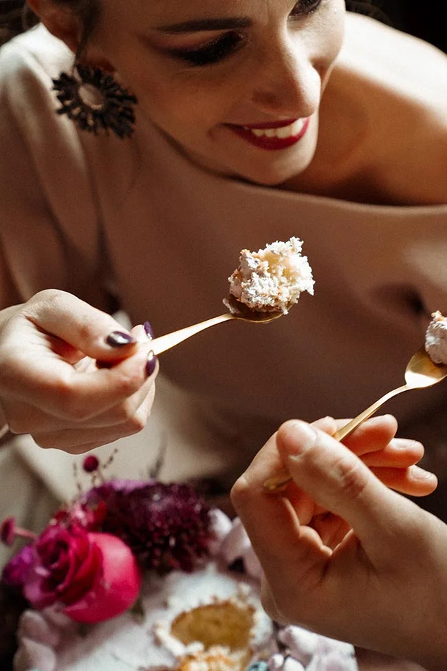 Gros plan d'un couple partageant un dessert blanc avec des cuillères dorées dans une ambiance tamisée et romantique.