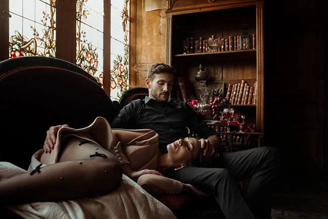 Couple élégant dans un décor sombre et luxueux, ambiance intime entre ombre et lumière.
