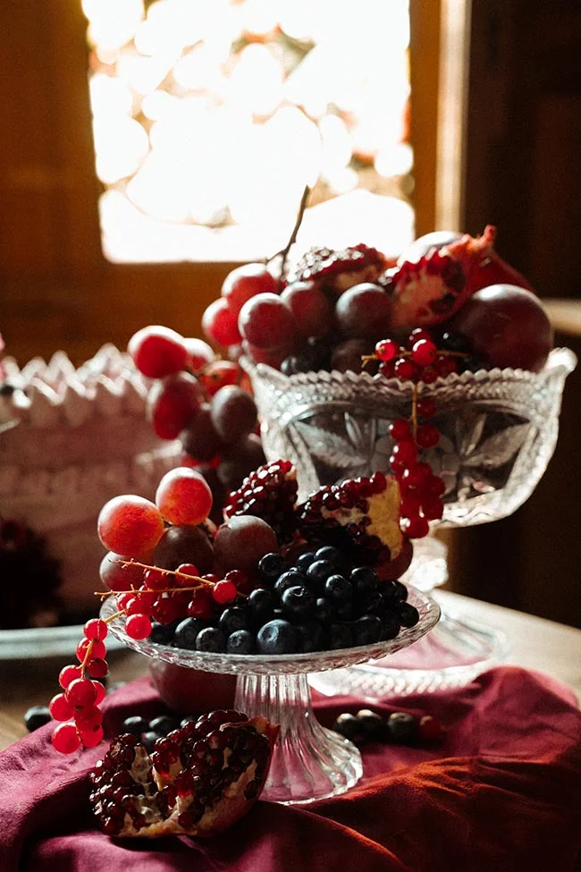 Composition élégante de fruits rouges et bleus dans des coupes en cristal, baignée d'une lumière douce et contrastée.