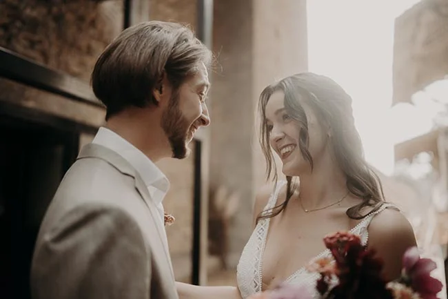 Jeunes mariés souriants et complices dans des tons neutres et lumineux, ambiance romantique et solaire.