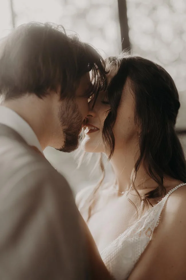Gros plan romantique d'un couple s'embrassant avec tendresse dans des tons chauds et lumineux.
