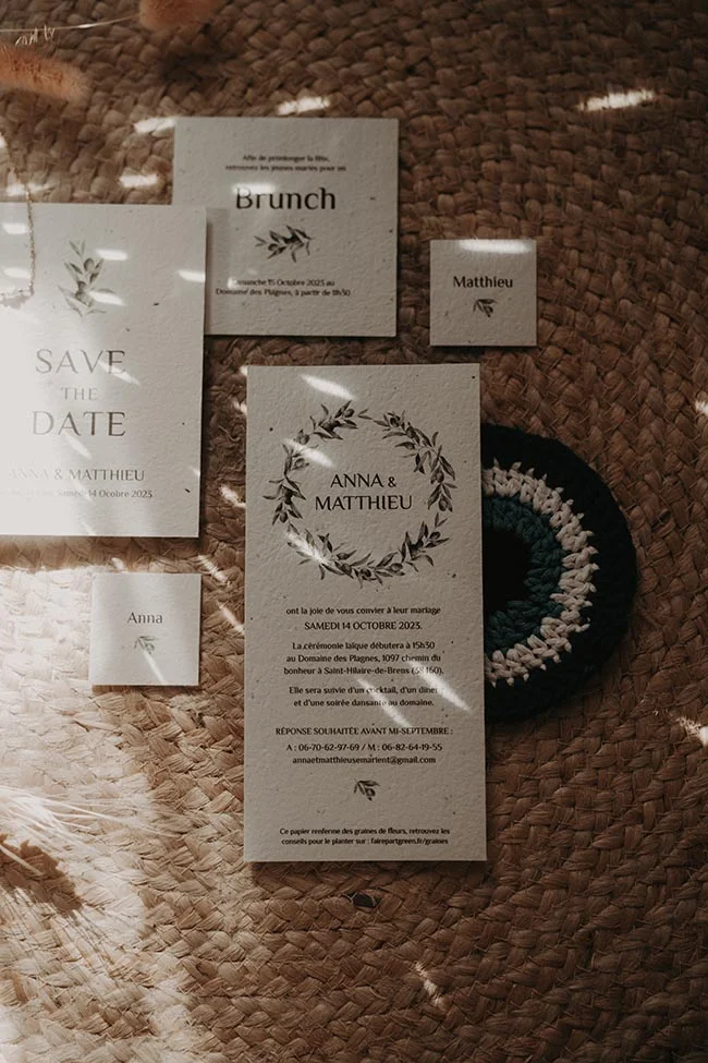 Papeterie de mariage beige et blanche sur un tapis en jute, ambiance naturelle et bohème.