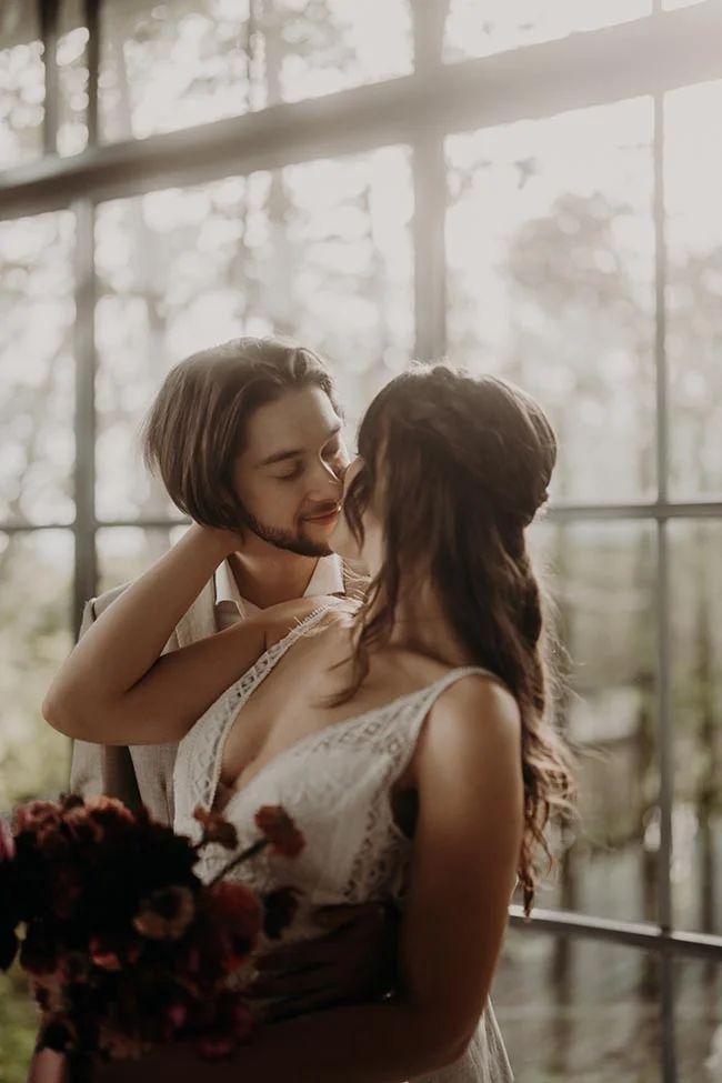 Couple enlacé dans une ambiance lumineuse et romantique, la mariée portant une robe blanche en dentelle.