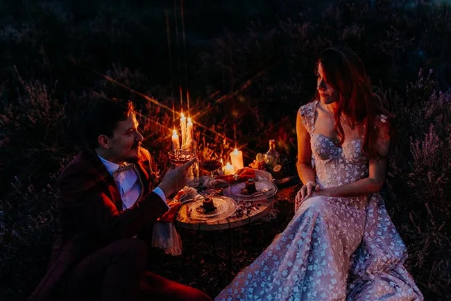 Couple élégant dînant aux chandelles lors d'un elopement nocturne et romantique en pleine nature.