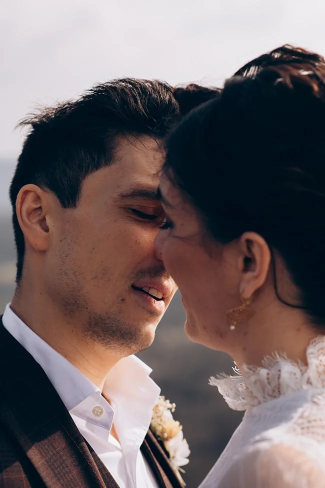 Gros plan romantique d'un couple de mariés se touchant tendrement le nez dans une ambiance lumineuse et douce.
