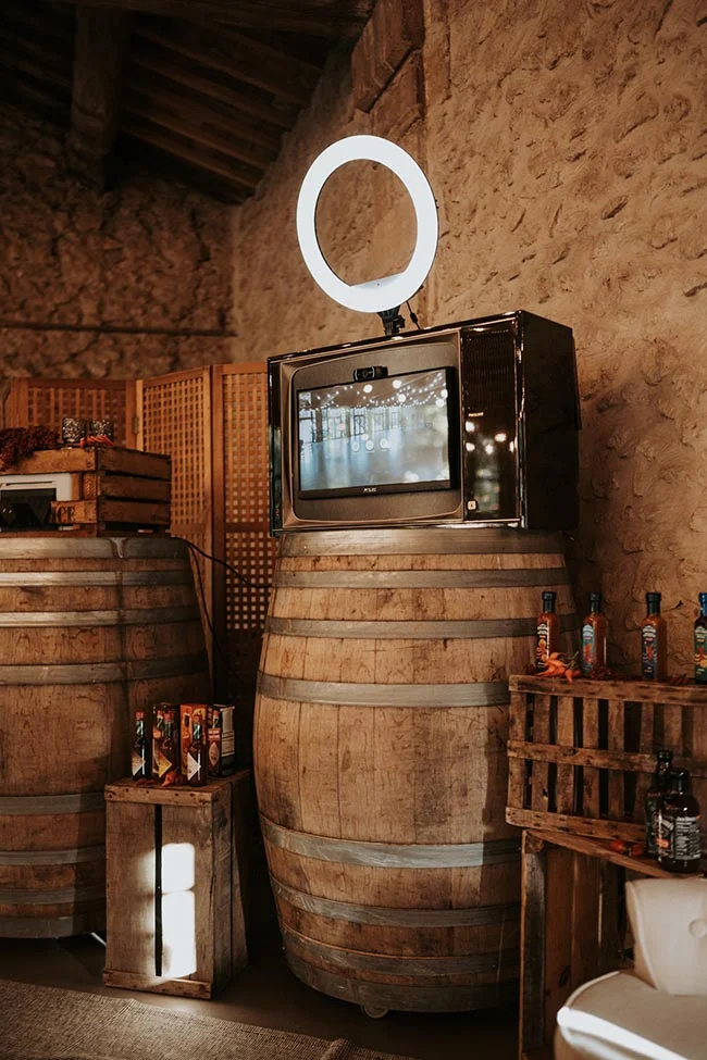 Un téléviseur vintage et un anneau lumineux posés sur un tonneau en bois dans un décor rustique et chaleureux.