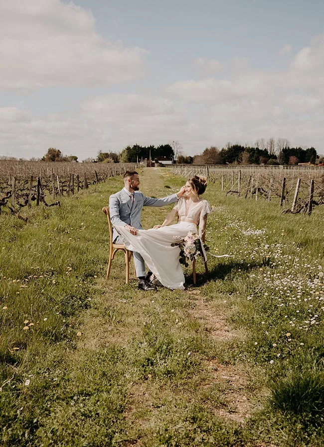 Couple marié posant avec romantisme dans un vignoble verdoyant, sous une lumière douce et naturelle.