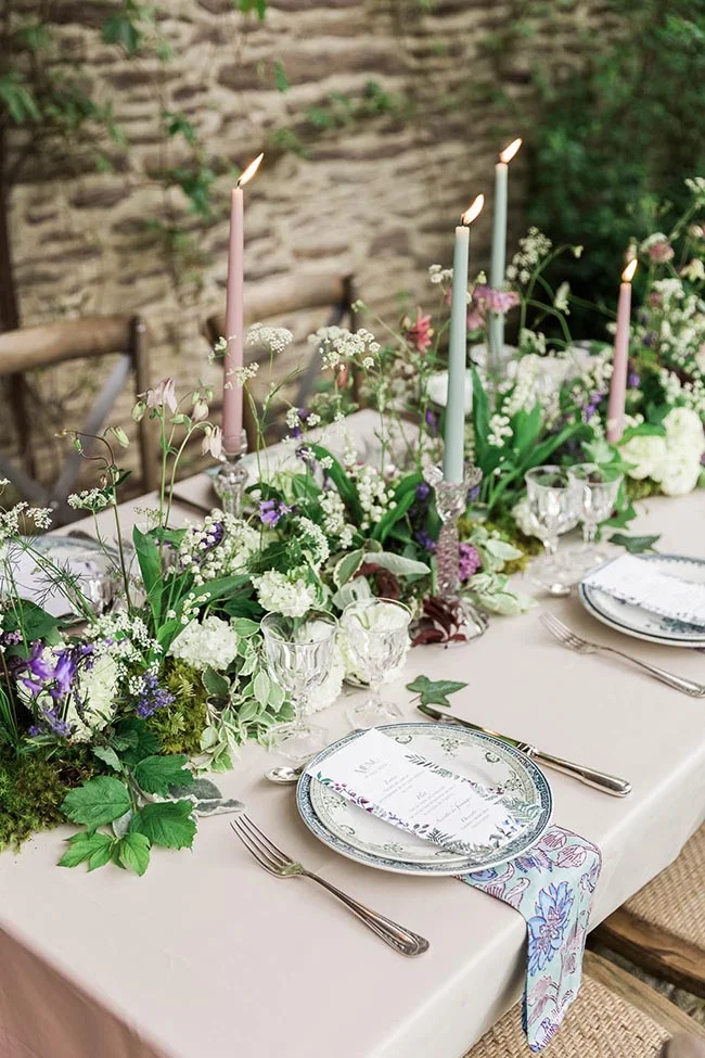 Table élégante et champêtre avec fleurs blanches, bougies pastel et vaisselle raffinée pour un mariage enchanté.