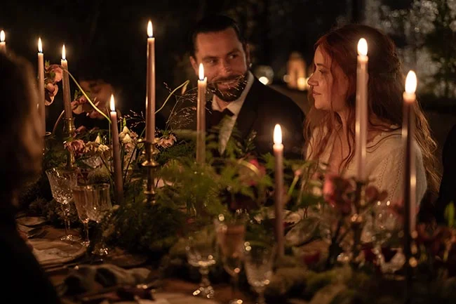 Dîner romantique aux chandelles avec un couple élégant dans une ambiance tamisée et naturelle.