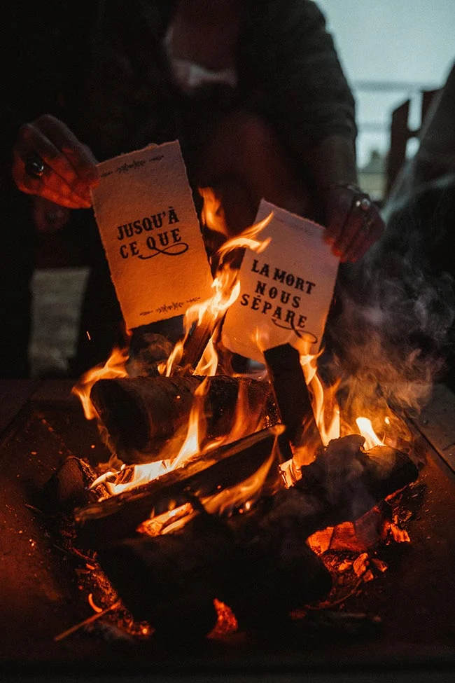 Une personne brûle dans un feu de camp deux feuilles de papier portant l'inscription « Jusqu'à ce que la mort nous sépare ».