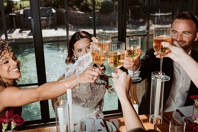 Des invités portent un toast au champagne lors d'un mariage lumineux et élégant en Provence.