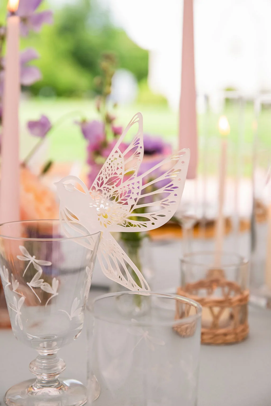 Décoration de table romantique avec un oiseau en papier découpé blanc, des bougies roses et des fleurs mauves.