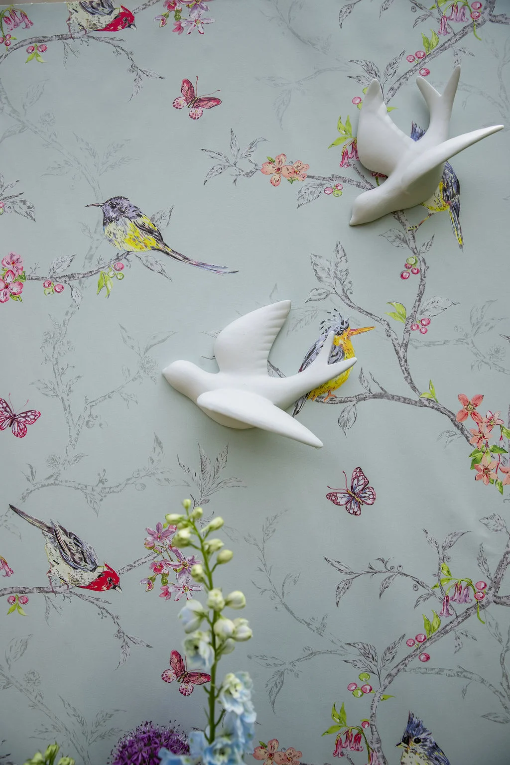 Décoration murale romantique avec papier peint floral et oiseaux, agrémentée de sculptures d'oiseaux blancs en relief.