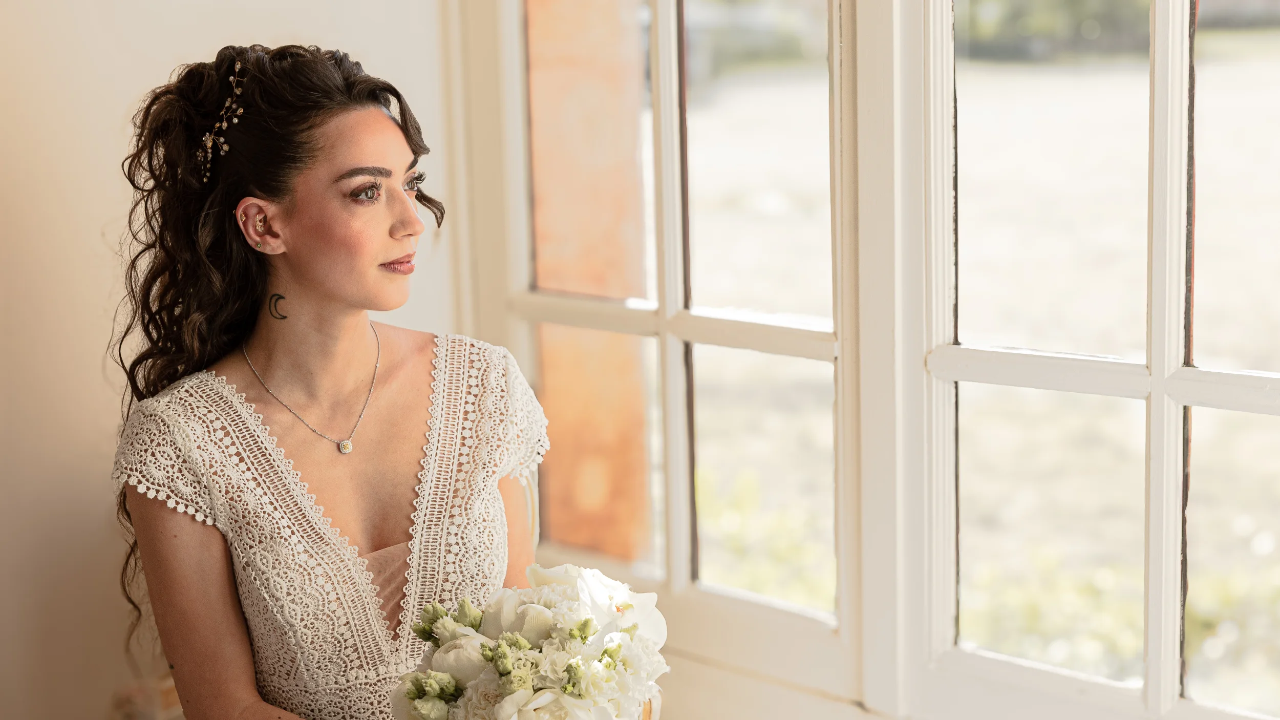 Une jeune mariée dans un robe de mariage intemporelle, tenant un bouquet de fleurs blanches, se regarde pensivement par