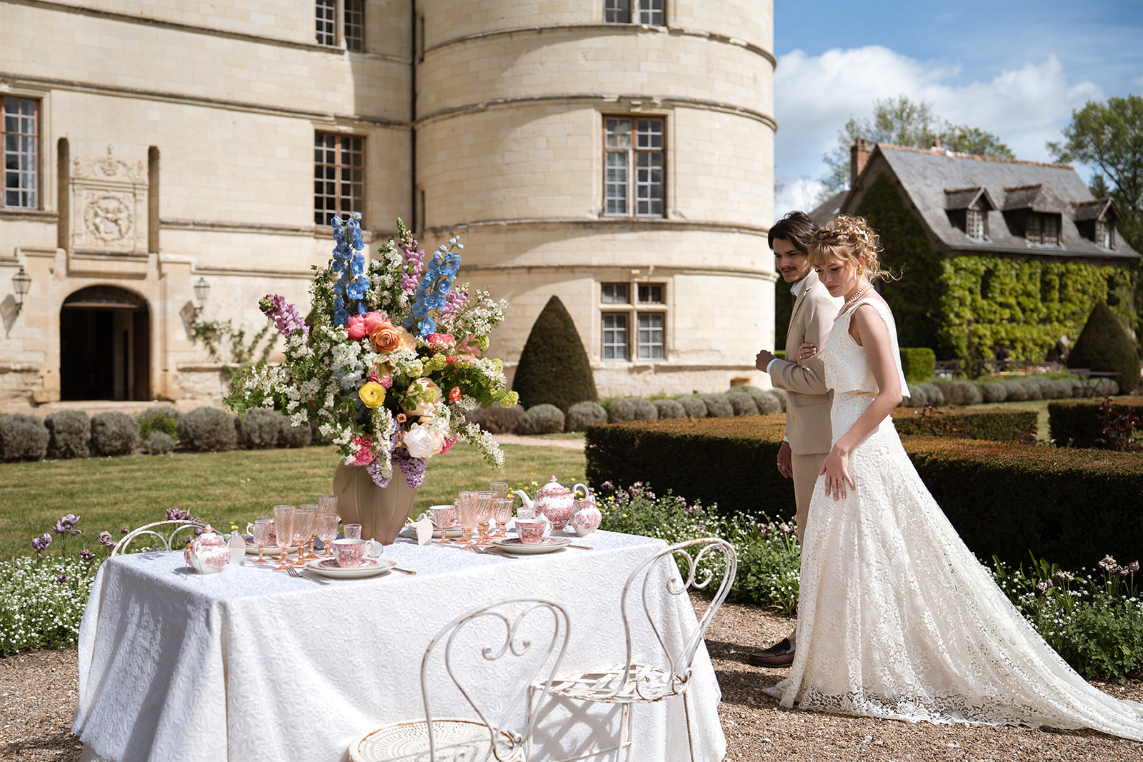 Couple de mariés devant un chateeu regardant une table où est disposée un service à thé