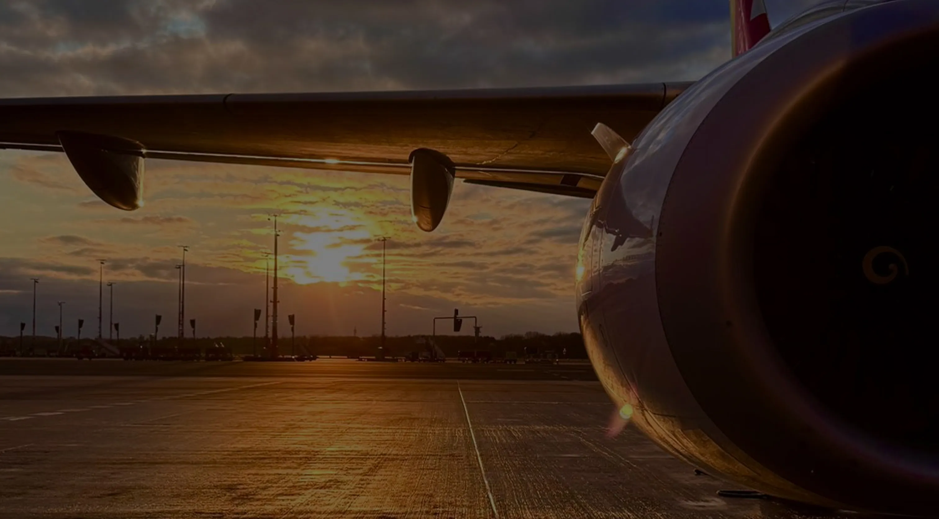 Triebwerk und Flügel eines Flugzeugs bei Sonnenuntergang am Flughafen.