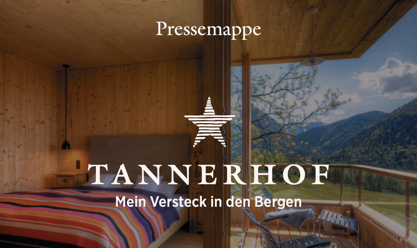 Holzschlafzimmer mit bunter Decke und Balkon mit Bergblick und Stühlen bei Sonnenlicht.