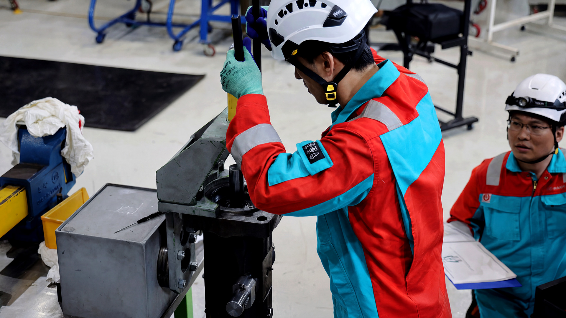 Marine engineering technicians inspecting and servicing industrial equipment in a workshop environment.