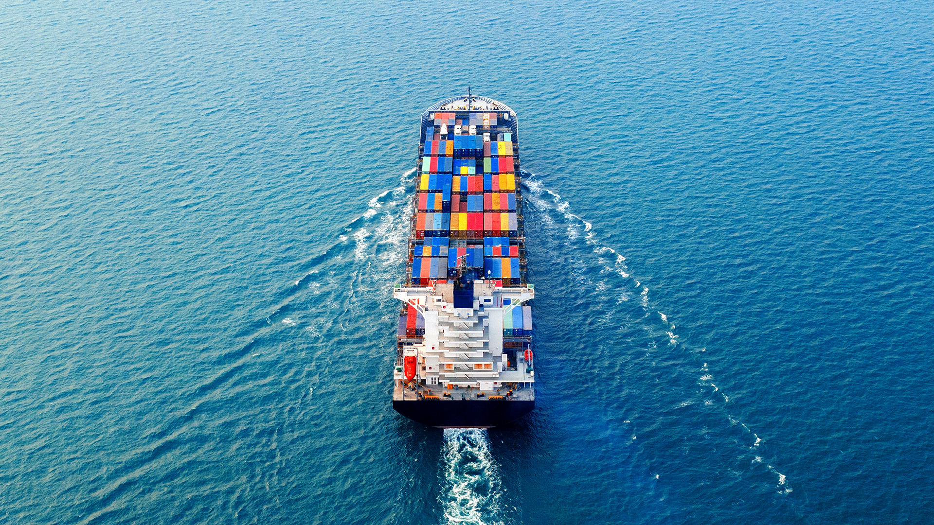 Aerial view of a merchant container ship transporting cargo across open ocean waters.