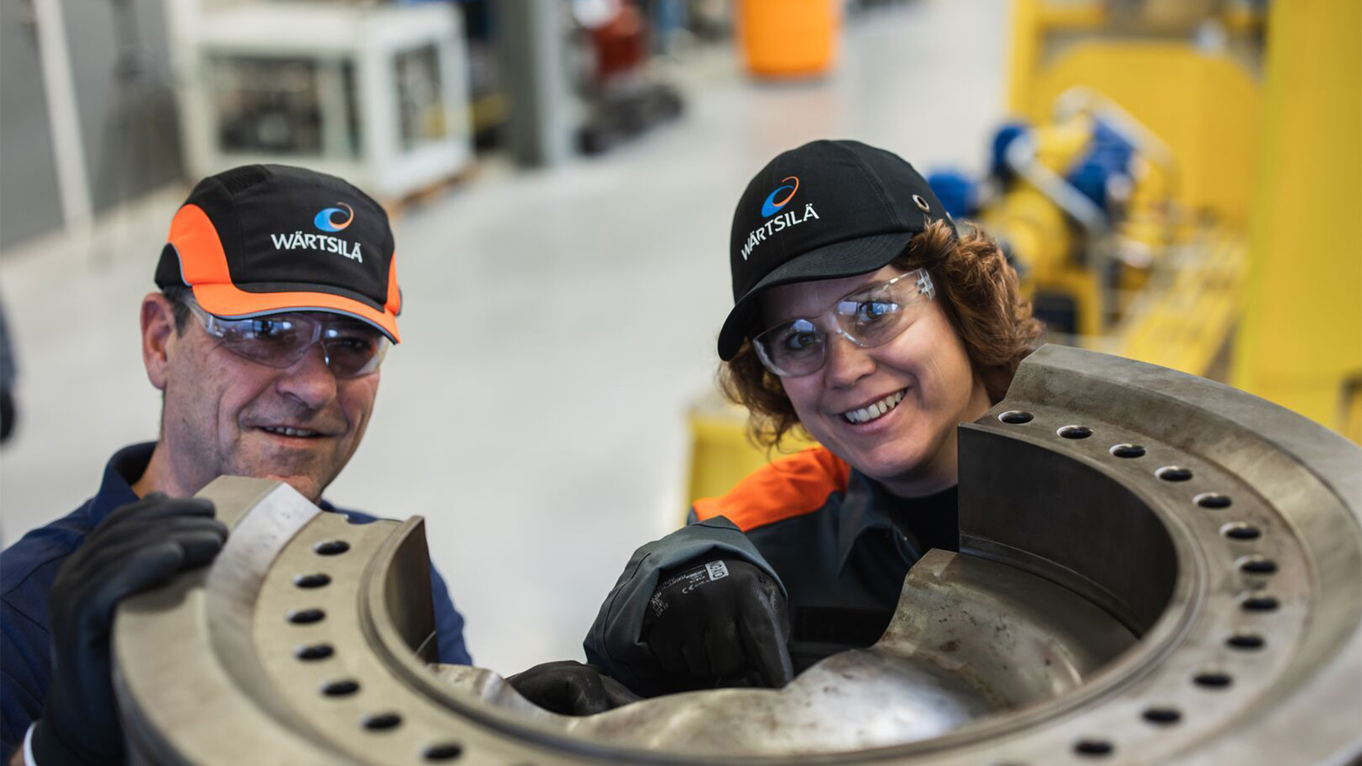 Marine engineering specialists inspecting large industrial vessel components in a workshop facility.