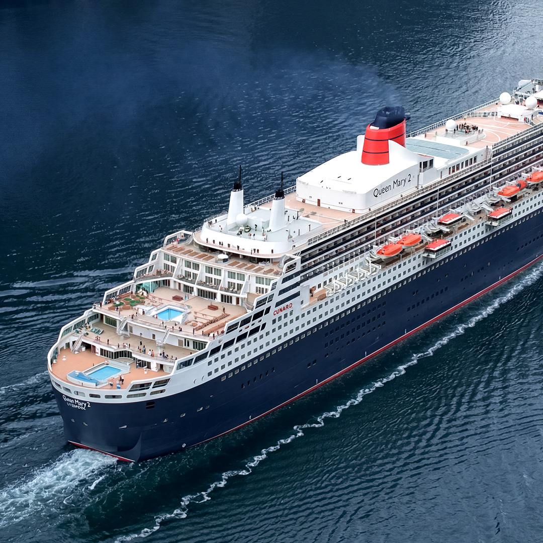 Queen Mary 2 cruise ship sailing through calm coastal waters.