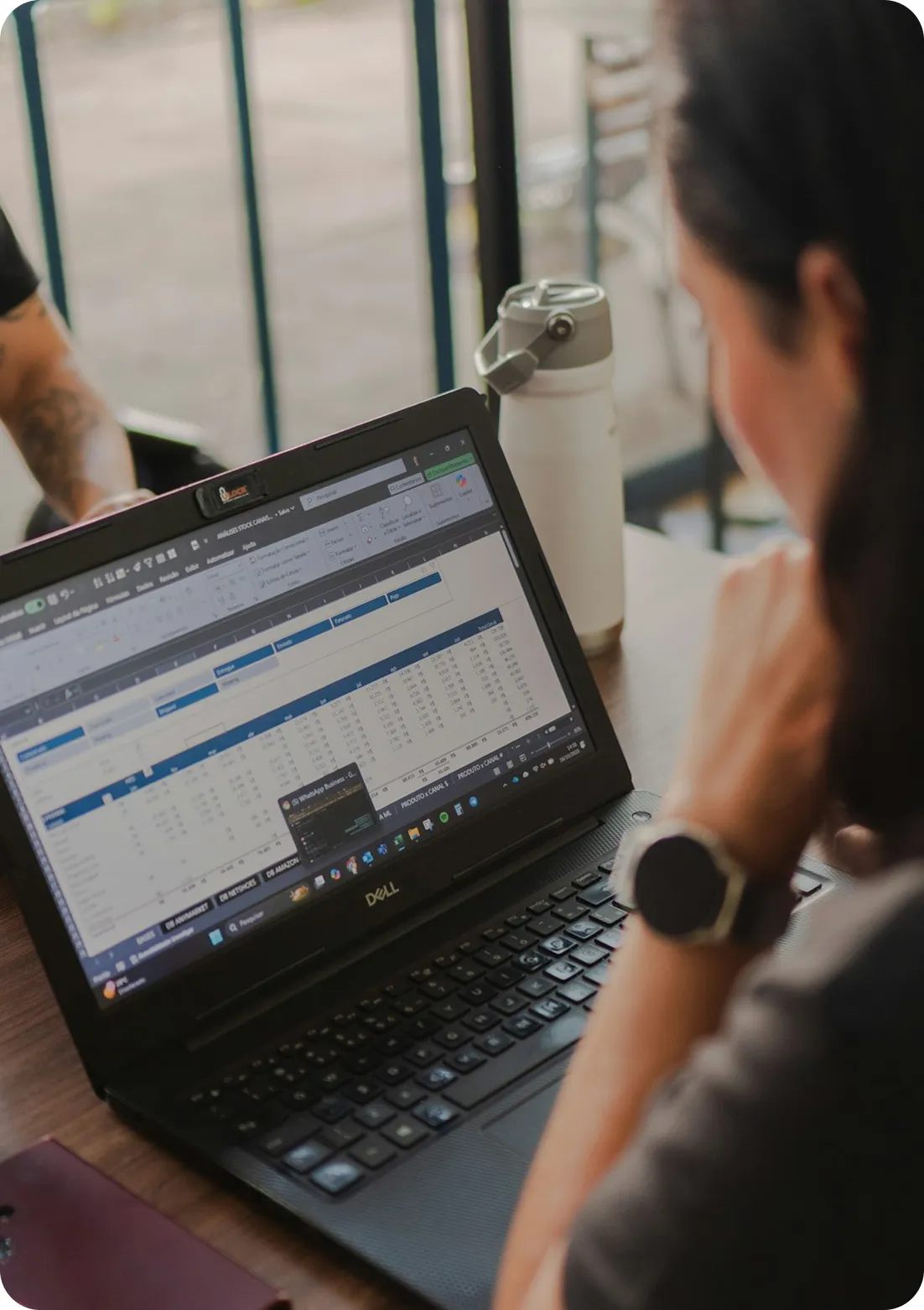 Person working on a Dell laptop displaying a detailed spreadsheet with financial data.