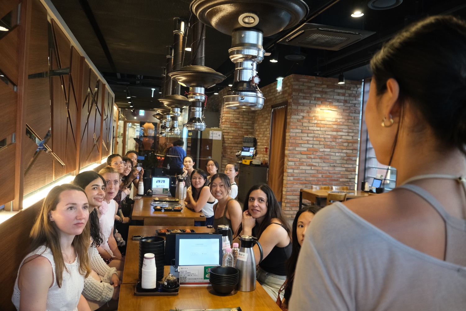 K-Pole retreat participants getting instructors by Haeri on how to best enjoy Korean BBQ at a restaurant in Seoul.