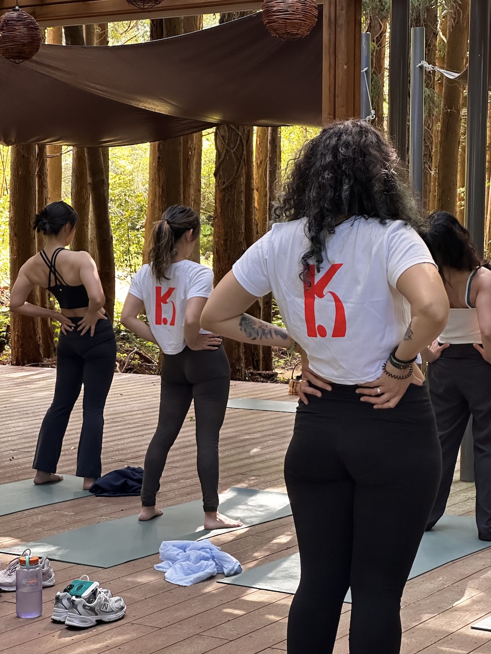 K-Pole Retreat participants doing morning yoga outdoors in a pergola in the woods on Jeju Island.