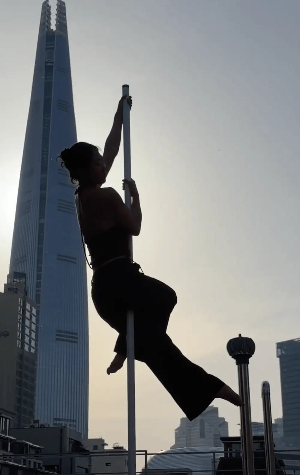 Haeri Park performing on a stage pole in front of Lotte World Tower in Jamsil, Seoul during K-Pole Retreat 2026.