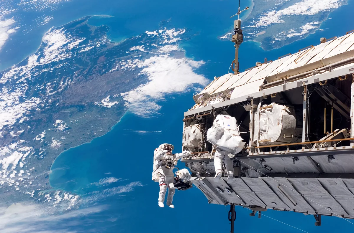 Ausseneinsatz auf der ISS (International Space Station), im Hintergrund die Südinsel (links) und die Nordinsel Neuseelands: Um die Astronauten zu schützen, sind heute schwere Raumanzüge nötig, die wenig Bewegungsfreiheit bieten. An Alternativen wird geforscht – ob die Aluminium-Beschichtung dereinst durch Schimmelpilz ersetzt wird?