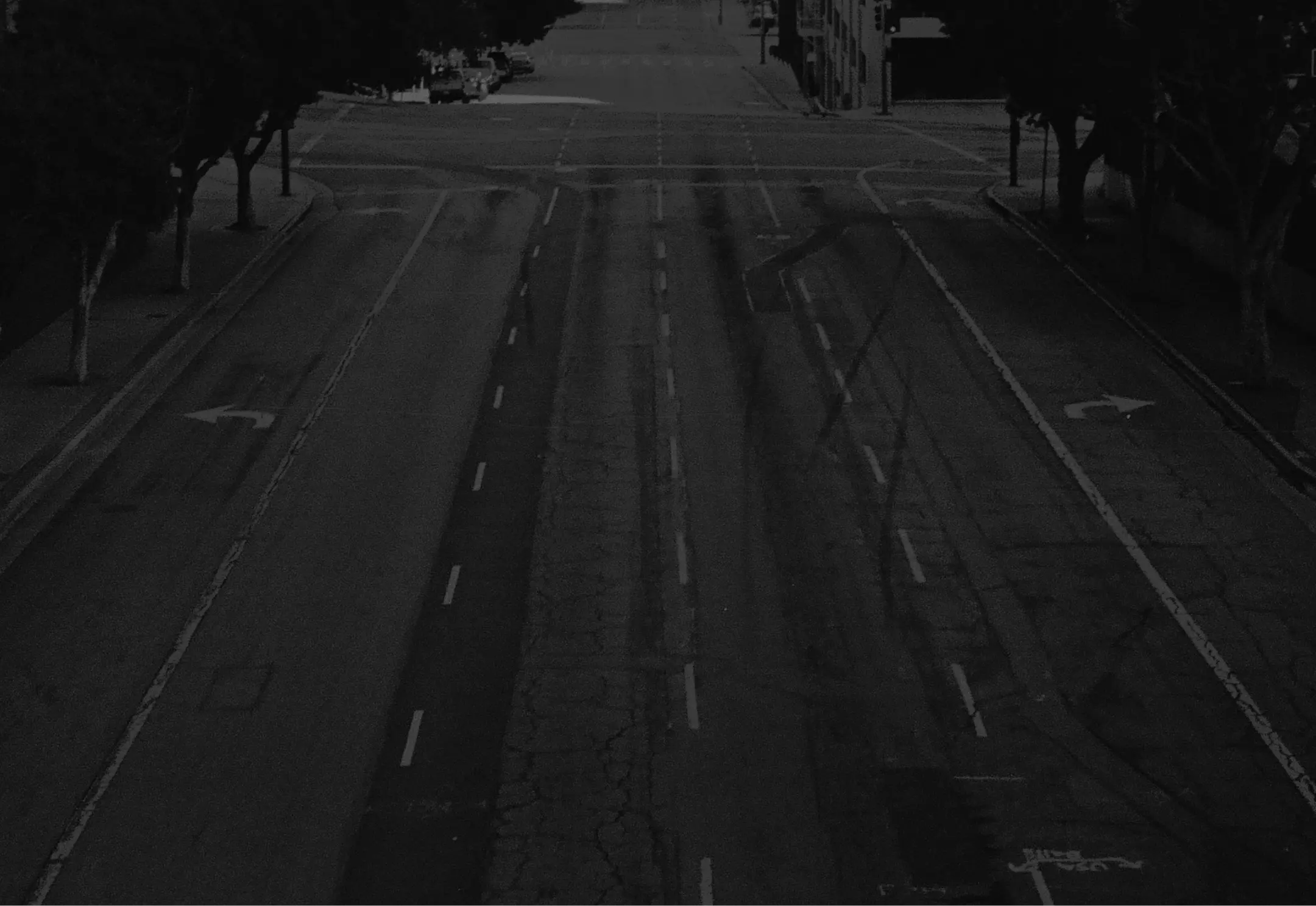 Empty urban street at night with multiple lanes and faded road markings.