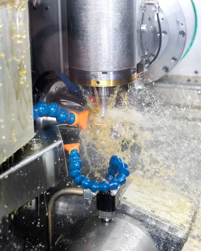 CNC machine cutting metal with coolant spraying around the spindle and cutting area.
