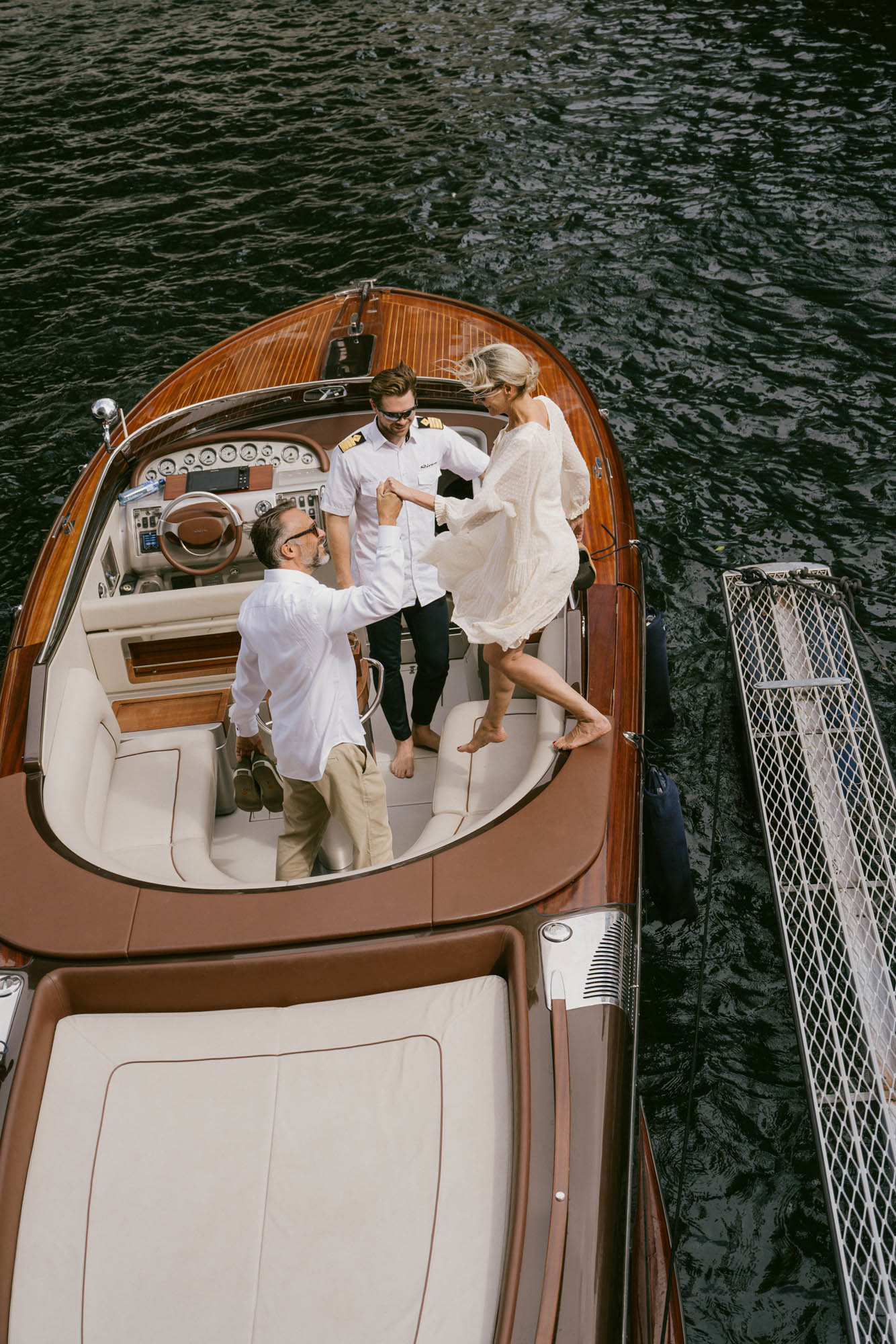 Guests boarding a classic wooden motorboat, assisted by a captain on a Norwegian fjord