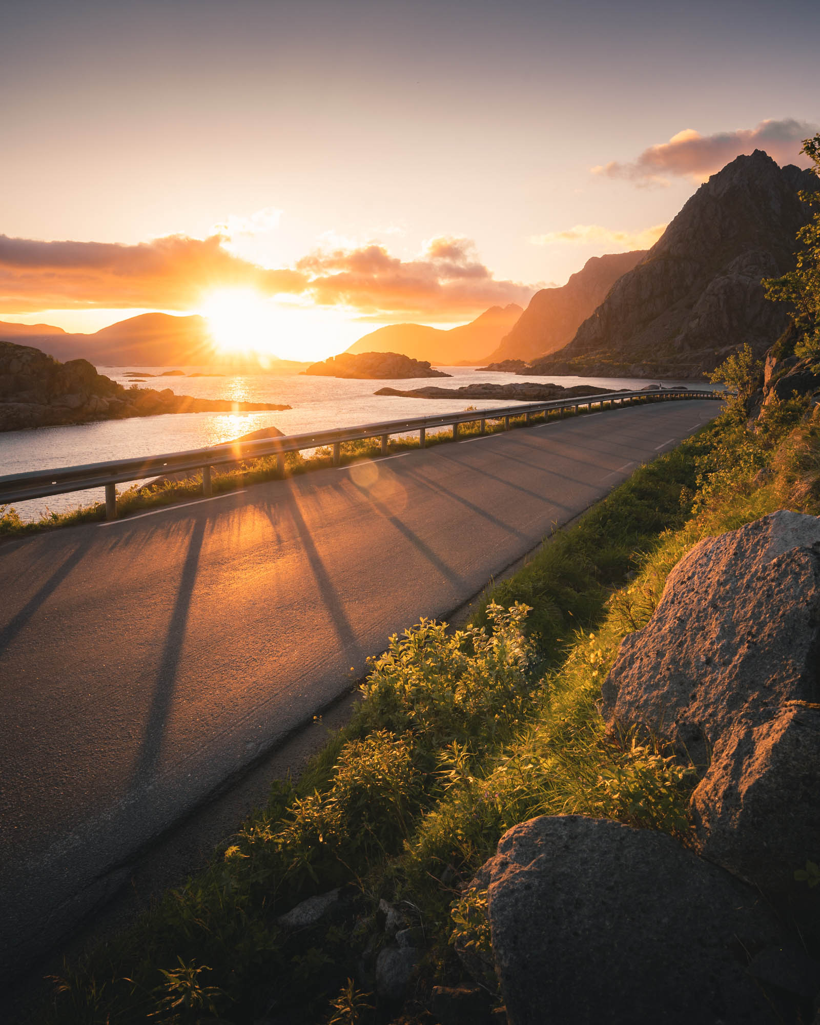 A winding coastal road bathed in midnight sun on the Lofoten Islands, Norway