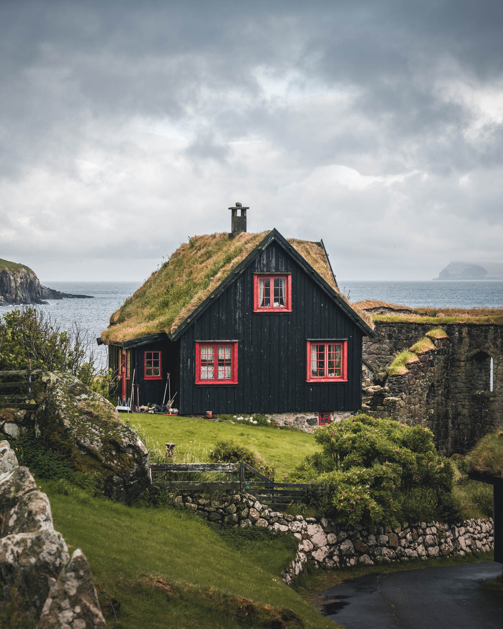 Faroe Islands — a traditional turf-roofed Faroese farmhouse with red-framed windows overlooking the Atlantic