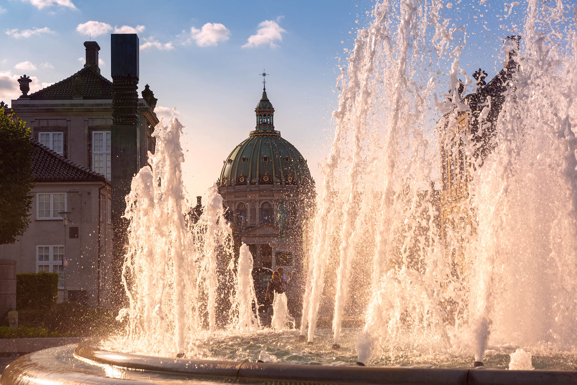 Denmark — the baroque dome of Frederik’s Church rising above a golden-lit Copenhagen fountain