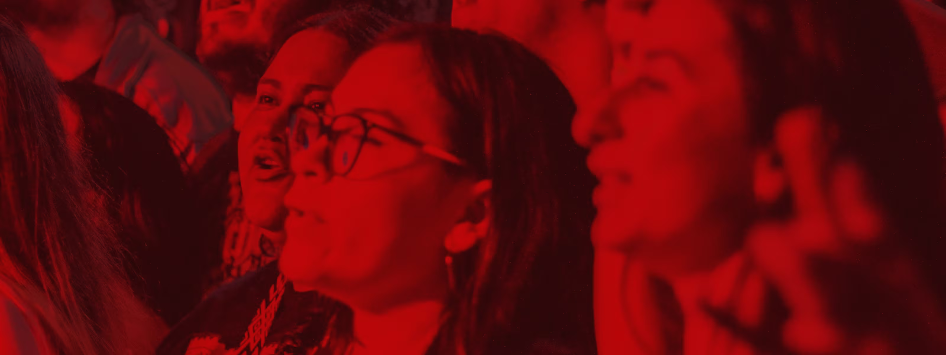 People in a crowd watching something, illuminated by red light.