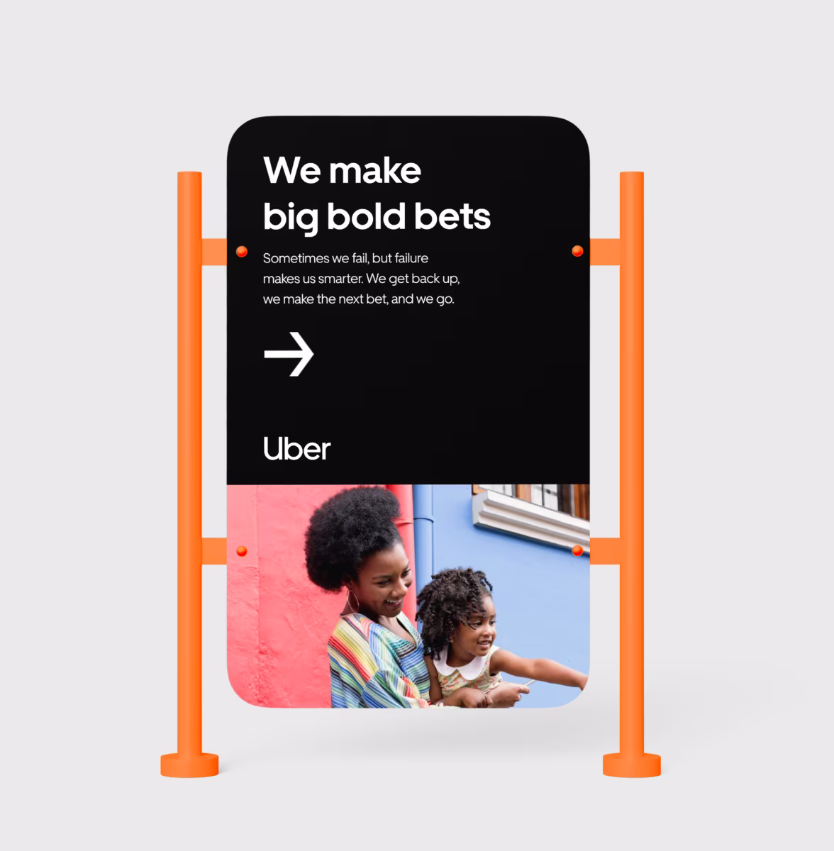 Sign with message about taking bold bets and a smiling woman holding a child pointing forward.