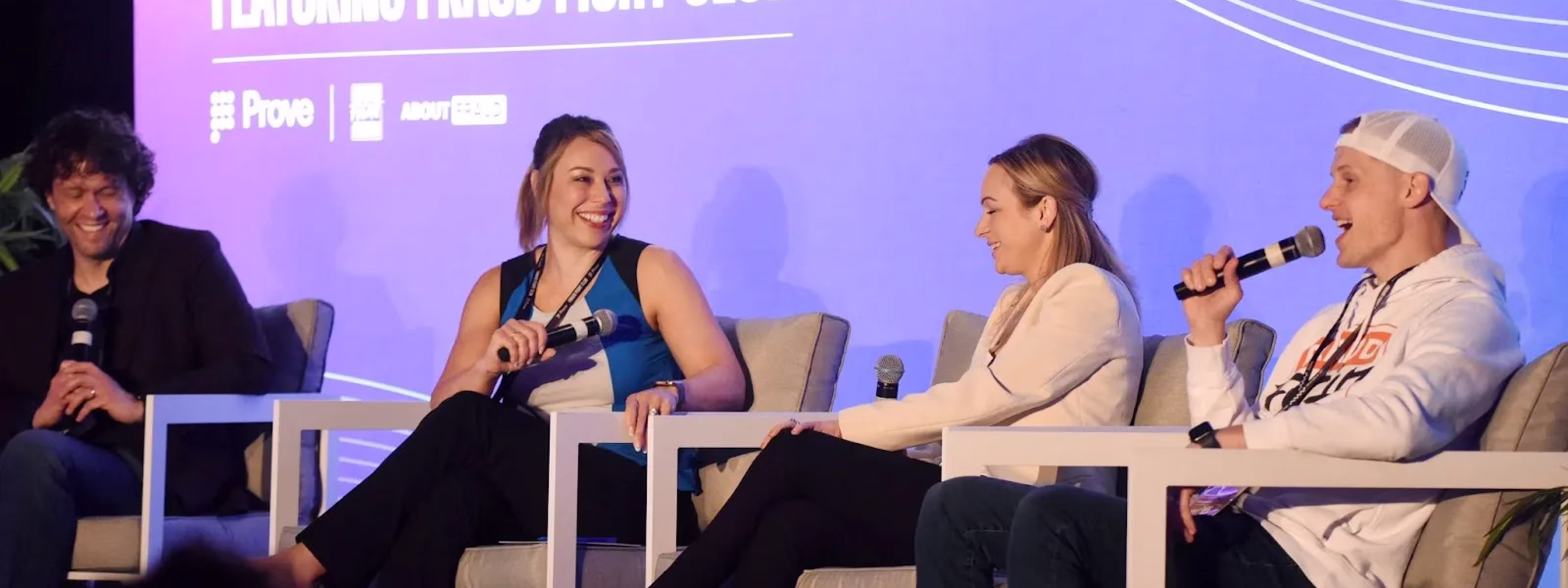 Four people seated on stage in a panel discussion, two women and two men holding microphones.