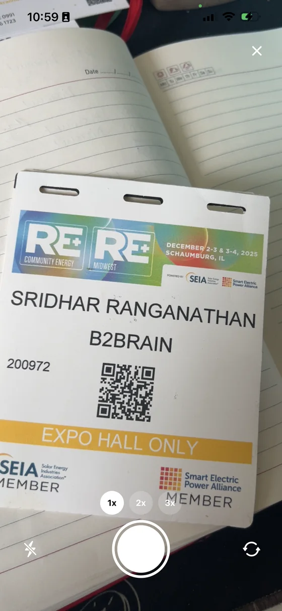 The camera view framing an attendee badge, with zoom controls and shutter