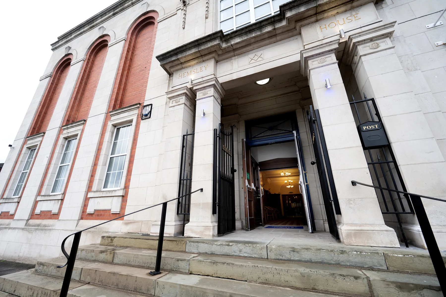 Front entrance of a stately building with open doors, steps, and pillars labeled Hemsley House.