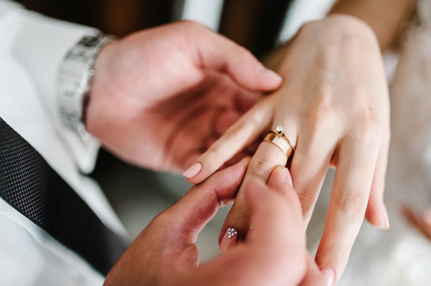 Close-up of a person placing a wedding ring on another’s finger during a ceremony.