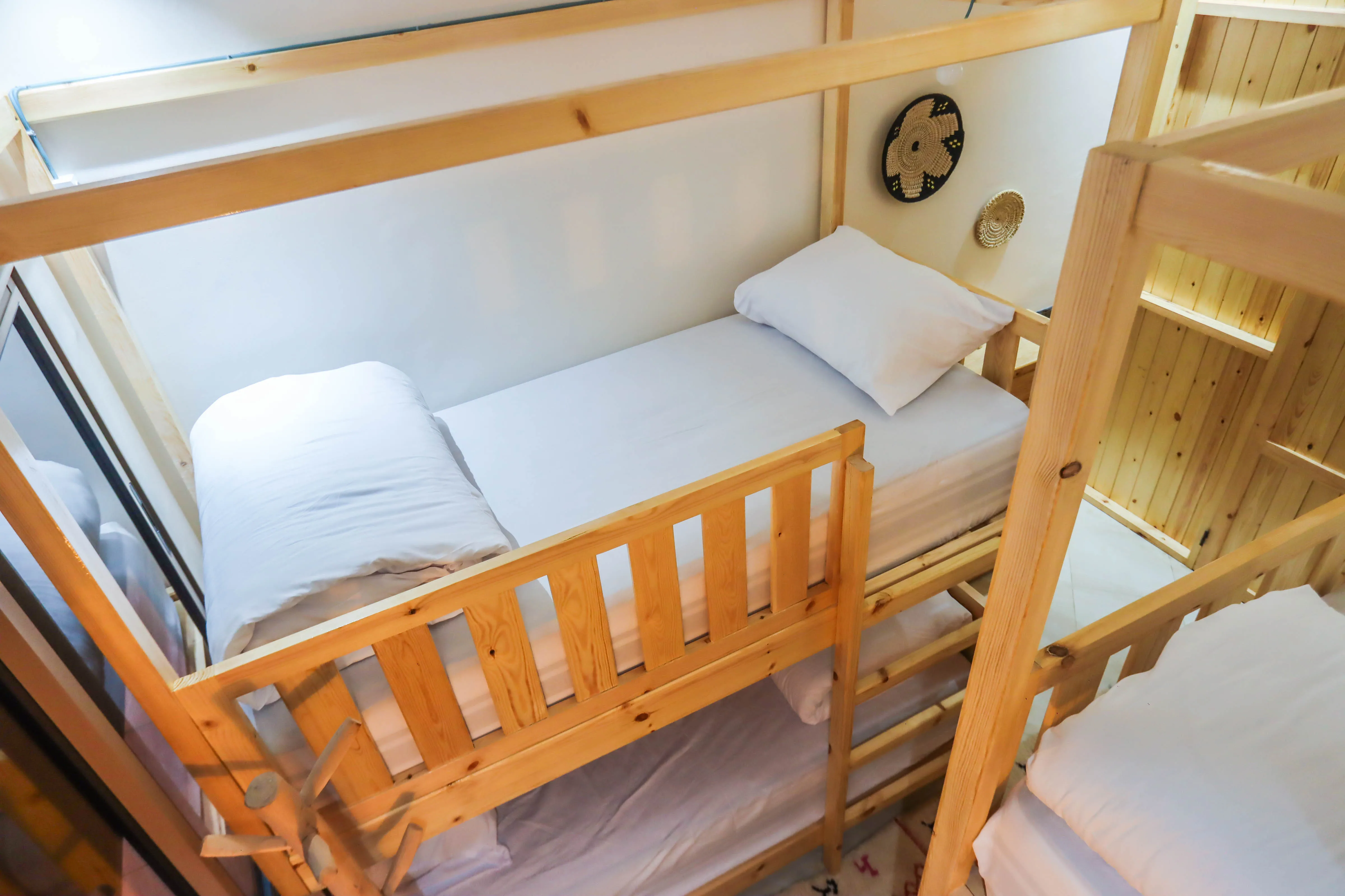 Wooden bunk beds with white pillows and linens in a cozy room with wooden walls.