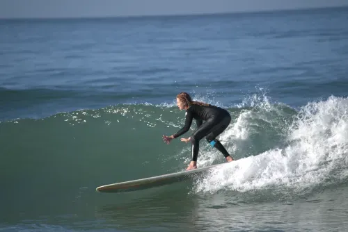 Woman in black wetsuit surfing on a wave in the ocean.