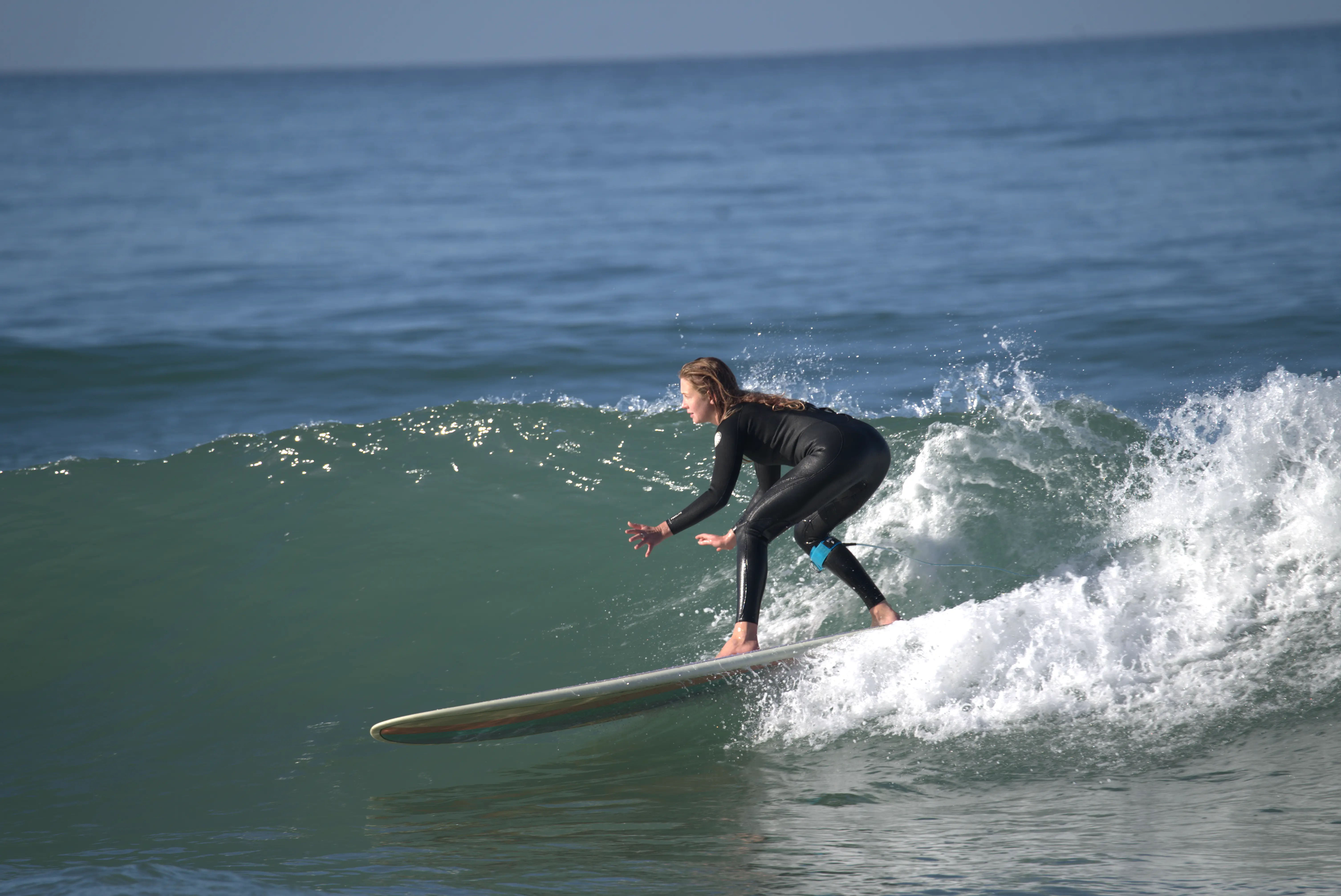 Woman in black wetsuit surfing on a wave in the ocean.